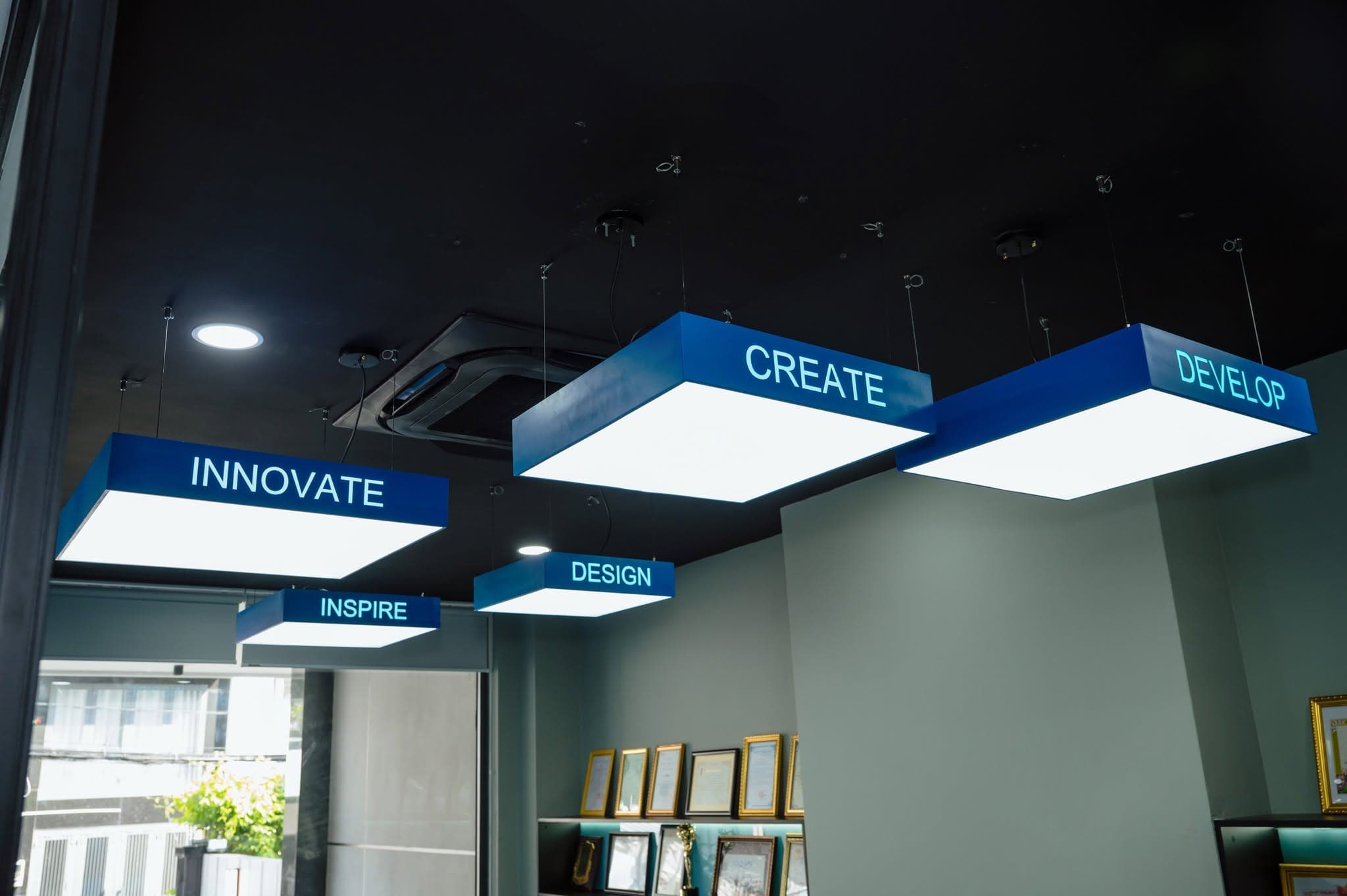 Illuminated ceiling boxes reading Inspire, Design, Develop, Create, Innovate.